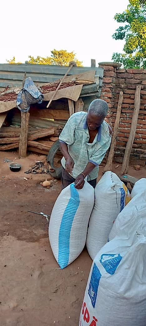 Shabani tends to large sacks of harvested grain near a partially dismantled structure on his farm.